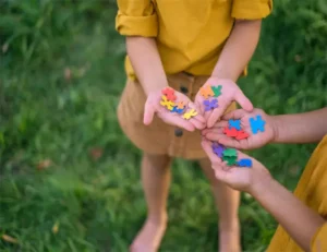 Crianças seguram peças de quebra-cabeças nas palmas das mãos como sinal de apoio e solidariedade às pessoas com autismo